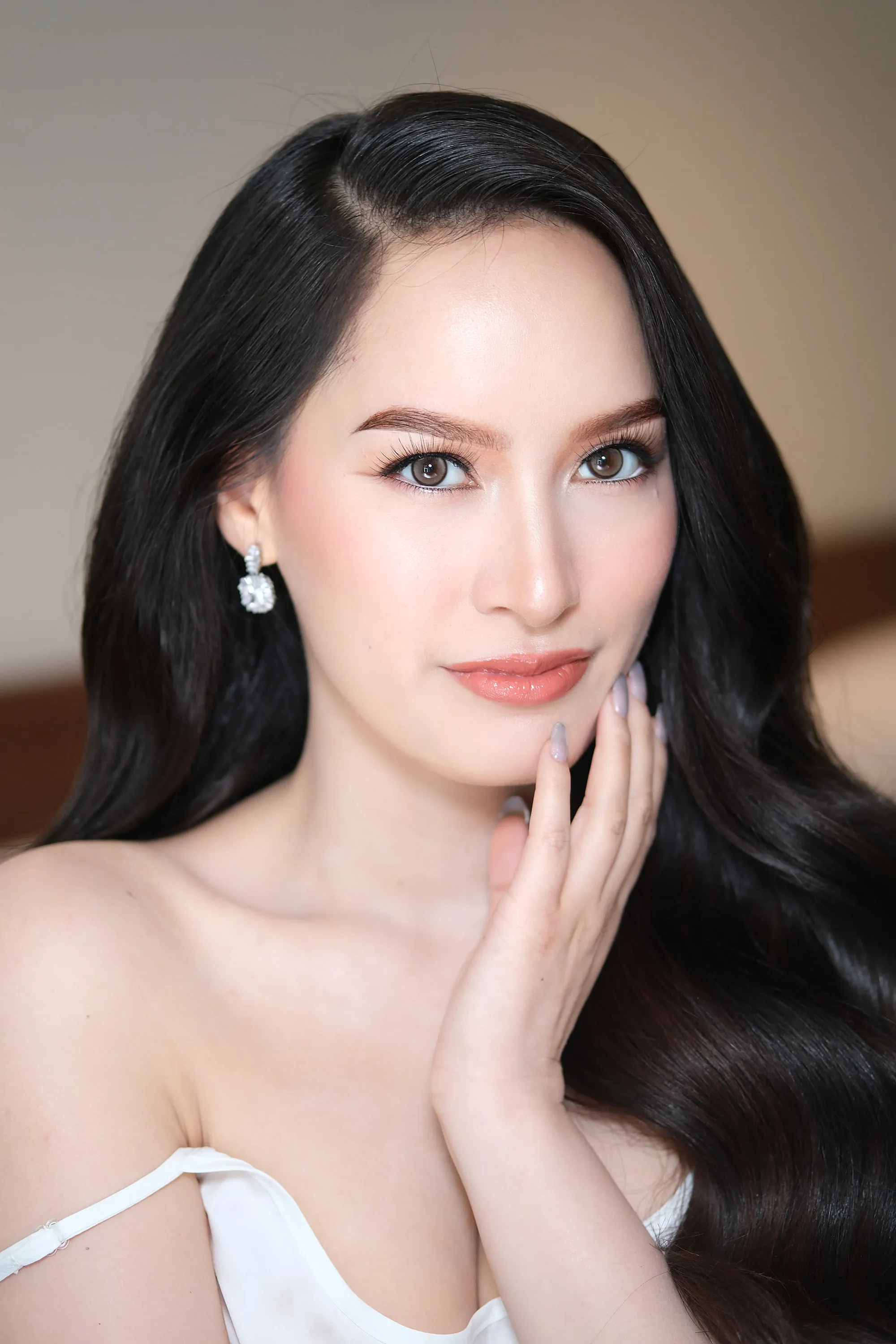 Bridal make-up with sculpted contour, a lifted lash line and a muted rose lip, worn with diamond drop earrings.